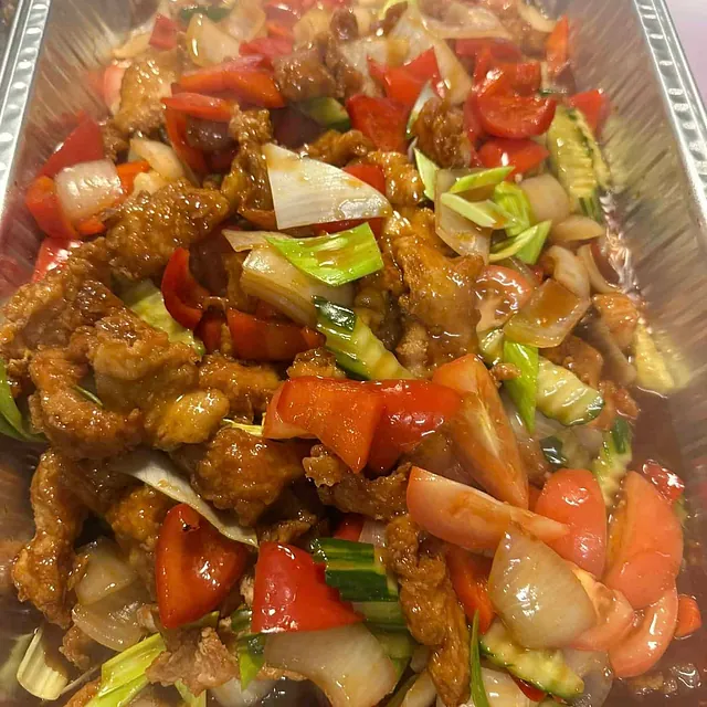 Fritert svinekjøtt med grønnsaker i saus, servert i aluminiumsform.